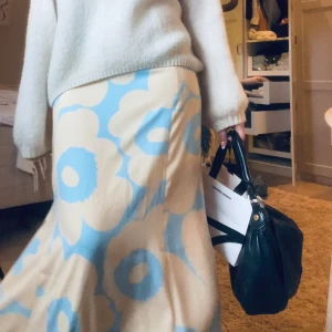 Marimekko långkjol - Säljer en långkjol från Marimekko med ett stort blommönster i blått och beige🌸 Kjolen har en lös passform och är tillverkad i ett mjukt och bekvämt material. Aldrig använt!