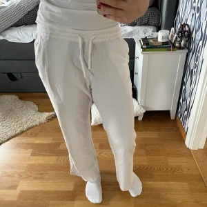 Vita linnebyxor  med snörning - Säljer ett par vita linnebyxor med elastisk midja och snörning från Lager 157. Byxorna har en avslappnad passform och är perfekta för en varm sommardag då de sitter luftigt och är gjorda av ett tunt material💕De är använda rätt mycket förra sommaren och har en liten fläck längst ner på vänsterbenet (se sista bilden) annars är de i bra skick💕Säljer då de är för korta på mig som är 172 cm💕Jag har även klippt bort lappen där bak och om du vill se bild är det bara att fråga!💕