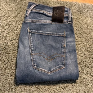 Hyperflex jeans Replay - Snygga blå jeans från Replay med Hyperflex-teknologi för extra komfort och stretch. De har en klassisk femficksdesign och en diskret broderad detalj på bakfickorna. Perfekta för en stilren look. Replay anbass. W32 passar som W31, L32