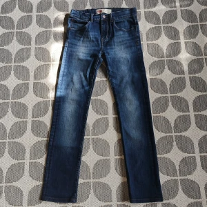 Levi's 510 Skinny Jeans - Snygga Levi's 510 skinny jeans i barn storlek med en klassisk blå denim färg . De har en smal passform och är perfekta för en stilren look. Byxorna har fem fickor och en knappgylf. 