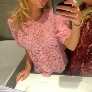 Rosa spetsblus - Säljer en söt rosa spetsblus med korta ärmar. Perfekt för en somrig look eller en festlig kväll. Blusen har ett vackert mönster och en luftig passform.