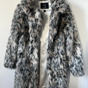 Grå pälsjacka från QED London - Säljer en snygg grå pälsjacka från QED London. Jackan har ett fluffigt och stilrent utseende med långa ärmar. Perfekt för att hålla sig varm och trendig.