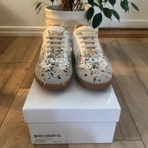 Färgstänkta sneakers - Masion marigielas Unika sneakers med färgstänk i olika nyanser på en vit bas. De är i storlek 43 och är oanvändna.