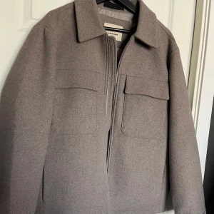 Brun jacka från Jack & Jones - Säljer en stilren jacka från Jack & Jones. Jackan har en dragkedja framtill och två stora fickor med lock på bröstet. Den är endast använd fåtalet gånger, den har inga märken eller skador. Nypris 1200kr perfekt nu till hösten.