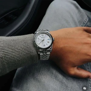Silverfärgad klocka från Seiko - Snygg och stilren silverfärgad klocka från Seiko med romerska siffror på urtavlan. Klockan har en klassisk design med en metallarmband och en tydlig vit urtavla. Perfekt för den som gillar en tidlös look.