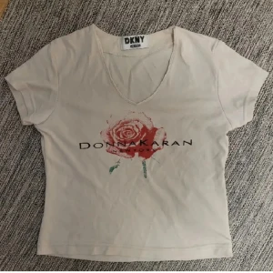 Vintage tshirt med tryck - Ljusbeige tshirt från DKNY (Donna Karan New York) med tryck och text i storlek S. Jättesnygg på, dubbeltyg vid bysten.