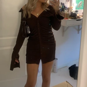 Klänning  - Brun klänning med knappar, har sytt in den själv vid låren då den va mer pösig där innan, går att sprätta upp om man vill det, inga defekter 