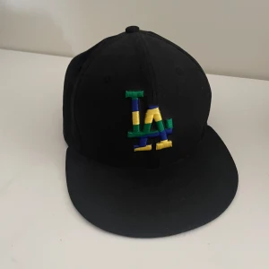 Svart keps från New Era - Riktigt snygg Los Angeles New Era keps i fint skick. Kepsen är 56,8 cm eller 7 1/8. Tyvärr var den för mig för liten. Skriv för vid frågor och pris kan diskuteras!