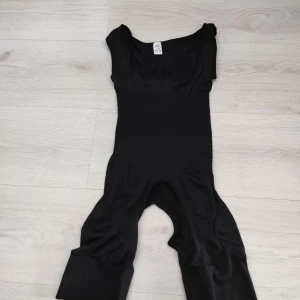 Svart shaping body L/XL - Säljer en svart onesie med breda axelband och en tight passform. Perfekt för en stilren look. Tillverkad i ett stretchigt material för extra komfort, lätt shaping