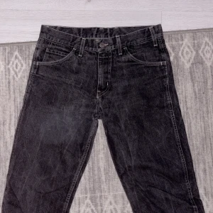 Svarta jeans med unik patch - Snygga svarta jeans med en cool, unik patch på baksidan. De har en klassisk femficksdesign och en knappgylf. Perfekta för en avslappnad stil.