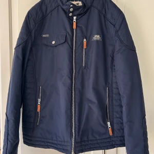 Blå jacka från Morris - Snygg blå jacka från Morris med dragkedja och flera fickor. Insidan har ett stilrent mönster i blått och vitt. Perfekt för en cool och avslappnad stil.