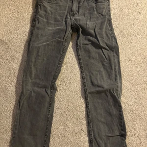 Grå jeans från Levi's - Säljer ett par grå Levi's jeans med straight passform. Klassisk design med fem fickor och knappgylf. Perfekta för en avslappnad stil.