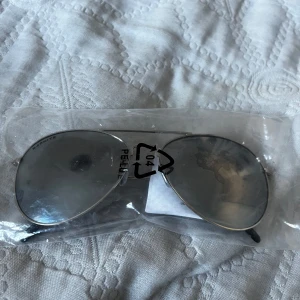 Silvriga pilotglasögon från Granite Eyewaer - Snygga silvriga pilotglasögon med spegelglas. Perfekta för en cool look och skydd mot solen. Kommer i en praktisk plastförpackning.