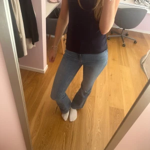 Blå bootcut jeans - Säljer ett par snygga blå jeans med bootcut passform. Jeansen har klassisk femficksdesign, bälteshällor och dragkedja med knapp. Materialet är mjukt denim som sitter skönt och ger en cool siluett. 