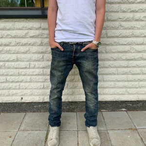 Blå jeans från &Denim, Storlek 30/32 - Säljer ett par blå jeans från &Denim med snyggt slitna detaljer och klassisk femficksmodell. Jeansen har rak passform och normal midja, tillverkade i bomull med en skön jeanskänsla. Perfekta till sneakers och t-shirt för en avslappnad look. Priset är inte hugget i sten!
