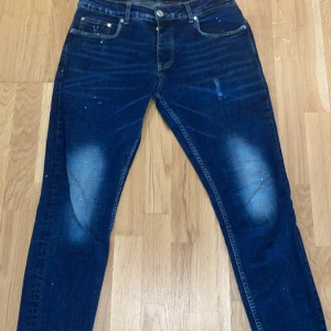 Mörkblå jeans från Cotton District - Snygga mörkblå jeans från Cotton District med slitningar och ljusa partier på knän och bakfickor. Klassisk femficksmodell med smal passform och gul kontrastsöm. Pris kan diskuteras 
