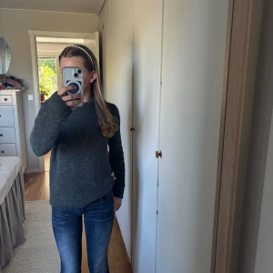 Mörkgrå stickad tröja Stockh lm - Mysig mörkgrå stickad tröja från Stockh lm med rund hals och lång ärm. Tröjan har en enkel, klassisk design och ett litet guldfärgat metallmärke vid nederkanten. Perfekt för kyliga dagar och enkel att matcha med jeans eller kjol. Den är perfekt nu till hösten börjar💕 det går att diskutera priset.