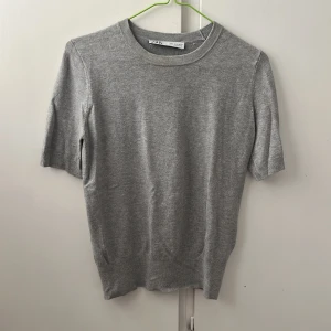 Grå stickad kortärmad tröja från Zara - Snygg grå stickad tröja från Zara med rund hals och korta ärmar. Den är i ett bra skick och har används bara ett fåtalgånger💕