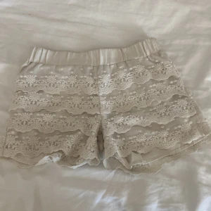 Vita spets-shorts från Lindex Kids - Supersöta vita shorts från Lindex Kids i storlek 134/140. De har flera lager med blommig volang. Perfekta för varma dagar när du vill ha något både gulligt och bekvämt. Säljer shorsten pga de har blivit för små för mig men endast använda några gånger 
