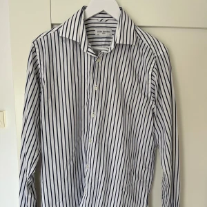 Skjorta från John Henric - Vit skjorta med svarta ränder från John Henric. Den är i storlek L (40). Mycket bra skick. 