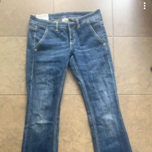 Blå bootcut jeans från Dondup - Snygga blå jeans från Dondup med bootcut passform och låg midja. Jeansen har klassiska kontrastsömmar, fem fickor och en läderpatch med logga bak. Tillverkade i mjukt denimtyg som sitter skönt och ger en avslappnad vibe.