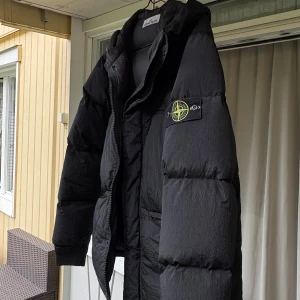 Svart dunjacka från Stone Island - Säljer en svart dunjacka från Stone Island (äkta) med ikonisk patch på armen. Jag har använt jacka ett par gånger men ser ut som ny. Jackan har luva, dragkedja och två fickor framtill. Riktigt bra dunjacka för vinter. 