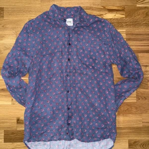 Blommig linneskjorta Oscar of Sweden - Snygg blå skjorta från Oscar of Sweden i 100% linne med rosa blommigt mönster. Fitted body-modell med långa ärmar och knappar framtill. Perfekt för dig som vill ha en stilren men ändå lekfull look. Mått: längd: 70cm. Bredd: 50cm. Nypris: 1699kr. Mitt pris: 159kr. Hör av dig vid frågor eller funderingar.