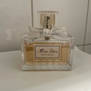 Miss Dior Eau de Parfum 50ml - Miss Dior Eau de Parfum i en elegant, rektangulär förpackning med en glittrig rosett vid halsen. Klassisk och feminin design med exklusiv känsla. Perfekt för dig som gillar lyxiga och ikoniska parfymer.   (Obs kartongen är inte kvar, den rosa färgen har bleknat bort lite men det påverkar inte doften)  Nypris: 1300kr    