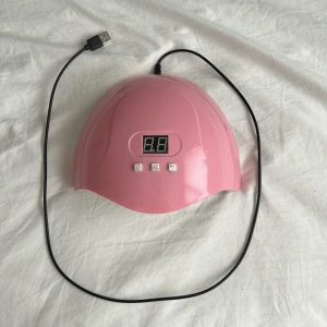 Rosa UV-lampa för naglar - Säljer en rosa UV-lampa för naglar med digital display och tre knappar för timerinställning. Lampan har flera LED-lampor på insidan och ansluts via USB-kabel. Perfekt för att fixa gelnaglar hemma. Smidig och lätt att använda.