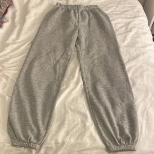 Grå mjukisbyxor med resår - Mysiga grå mjukisbyxor med resår i midjan och vid bensluten. Perfekta för chill dagar hemma eller när du vill vara extra bekväm. Klassisk modell i mjukt material.