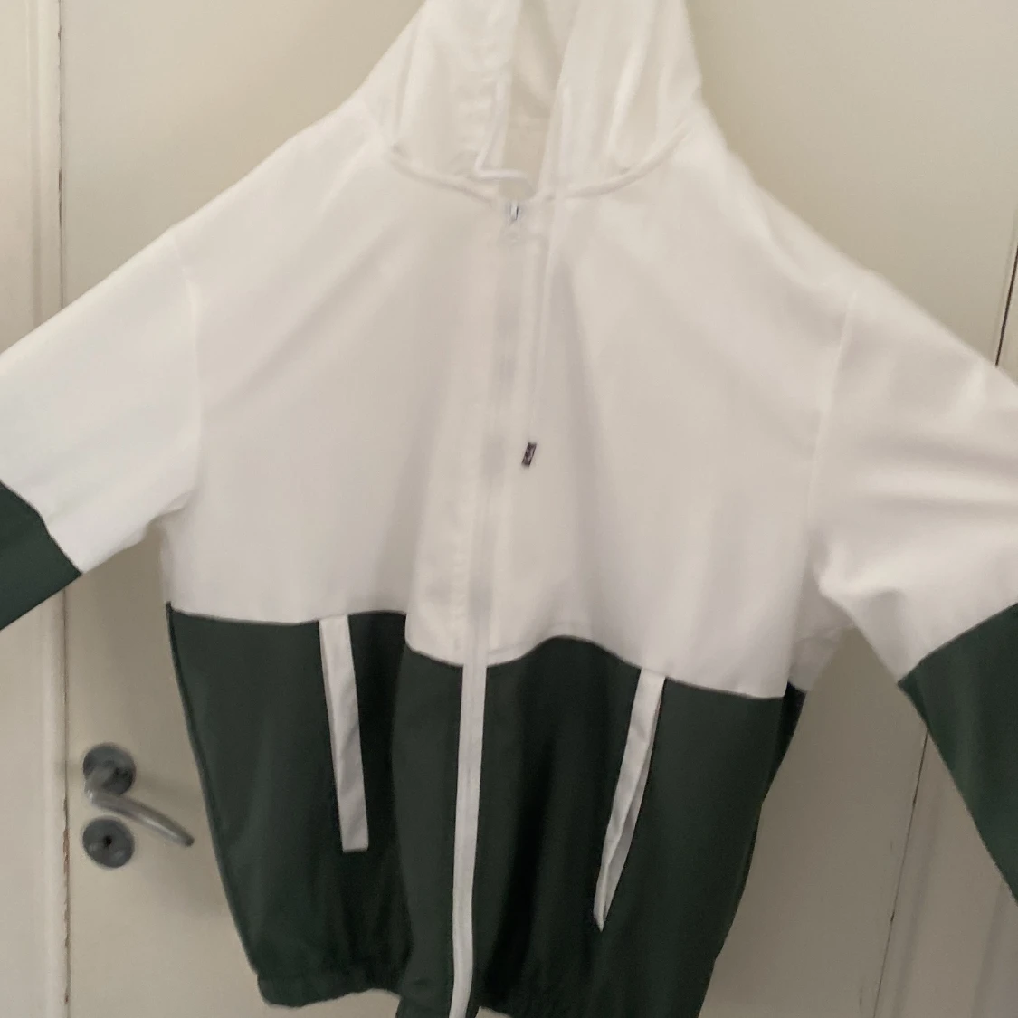 Vit och mörkgrön vindjacka med huva