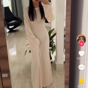 Beige långklänning  - Supersnygg ljus långklänning med vida ärmar och ribbad struktur. Klänningen har snörning i sidan som ger en cool detalj och sitter figurnära över kroppen. Perfekt för dig som gillar minimalistisk stil med en twist. Materialet känns mjukt och stretchigt. max använd 2 ggr