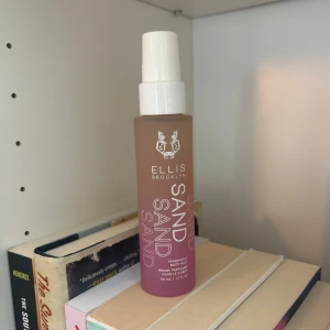 Ellis Brooklyn Sand Body Mist - Fräsch body mist från Ellis Brooklyn i doften Sand. Flaskan är frostad och har en beige-rosa ton med vit text och logga. Praktisk sprayfunktion med vit kork. Rymmer 50 ml och är perfekt att ta med i väskan. Ny