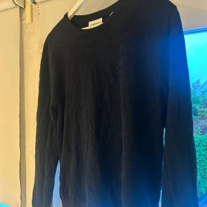 Svart tröja från Lindbergh White M - En stilren svart tröja från Lindbergh White i storlek M. Tröjan har rund halsringning, långa ärmar och är tillverkad i ett mjukt material som passar perfekt till lager-på-lager. Enkel och klassisk design som funkar till många olika looks.