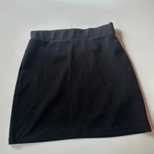 Svart kortkjol från NLY Trend - Enkel och stilren svart kortkjol från NLY Trend i figurnära modell. Kjolen har en hög midja och är sydd i ett mjukt, stretchigt material som sitter snyggt. Perfekt att matcha med en crop top eller oversized hoodie.