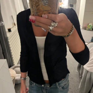 mörkblå kofta  - Snygg svart kavaj från Street One i klassisk modell. Tunn och lätt, perfekt att slänga över en topp eller t-shirt. Kavajen har lång ärm och en enkel, öppen front utan knappar. Passar till jeans eller kjol för en clean look.