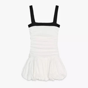 Helt ny vit kortklänning med svarta axelband - Supersöt vit kortklänning med svarta breda axelband och fyrkantig urringning. Klänningen har en rynkad överdel och en puffig kjol som ger en cool och trendig siluett. Perfekt för dig som gillar att sticka ut med stilren kontrast. Köpt för bara någon månad sen och använd en gång, slutsåld på hemsidan!