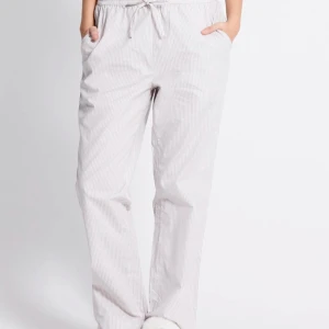 Randiga pyjamasbyxor  - Snygga pyjamasbyxor i färgen beige och vitt med tunna ränder och har storleken XS. Byxorna har elastisk midja med snörning och raka ben, perfekta för chill dagar. 