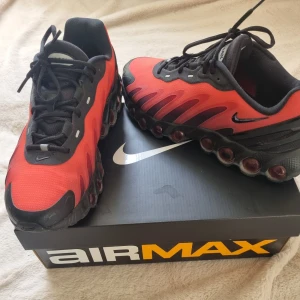 Nike Air Max DN8 röd/svart strl 43 - Nike Air Max DN8 sneakers i rött och svart med cool design och synliga Air Max-dämpningar i sulan. Ovandel i syntetmaterial och mesh, svarta snören och detaljer. Perfekta för dig som vill sticka ut med en modern och sportig look. Skorna är nästintill helt nya, haft på mig de 1 gång.                          Original nike låda och kvitto finns att visa