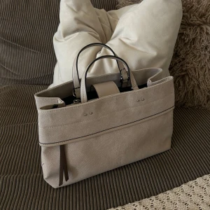 SLUTSÅLD ONLINE - Beige handväska från Parfois  - Stilren beige handväska från Parfois med både korta handtag och axelrem. Väskan är rymlig med flera fack, dragkedja. Perfekt för att bära laptop och allt du behöver till skolan eller stan ☕️ Slutsåld online. Helt ny med prislapp! 