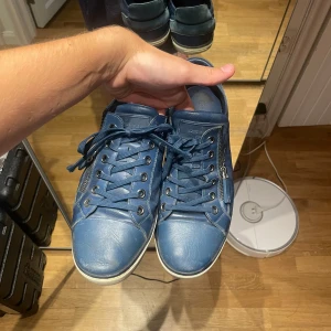 Blå Louis Vuitton sneakers med dragkedja - Nypris: 6000kr. Snygga blå sneakers från Louis Vuitton med det klassiska rutmönstret och coola dragkedjor på sidorna. Materialmix av skinn och mocka ger en lyxig känsla. Perfekta för dig som vill sticka ut med exklusiva detaljer. Har haft de uppe tidigare för 3500kr. 