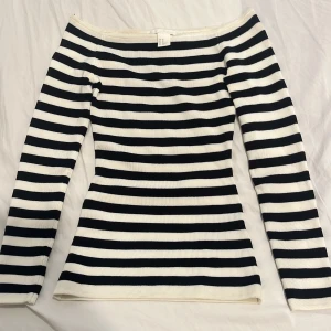 Randig offshoulder topp från H&M XS - Snygg offshoulder topp från H&M i storlek XS. Svarta och vita horisontella ränder ger en klassisk vibe. Långärmad och figurnära passform som sitter riktigt snyggt. Ribbad struktur i materialet för extra stilpoäng.