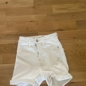 Vita jeansshorts från Perfect Jeans XS - Snygga vita jeansshorts från Perfect Jeans, modell Molly. De är högmidjade med klassisk femficksdesign, knapp och dragkedja framtill samt uppvikta benslut. Perfekta för varma sommardagar och lätta att matcha med allt.