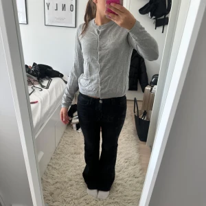 Grå kofta med knappar - Snygg grå kofta med rund hals och knappar hela vägen framtill. Långärmad och i mjukt, tunt material som känns skönt mot huden. Perfekt att slänga över en t-shirt eller ha som lager. Enkel och stilren design som passar till det mesta.