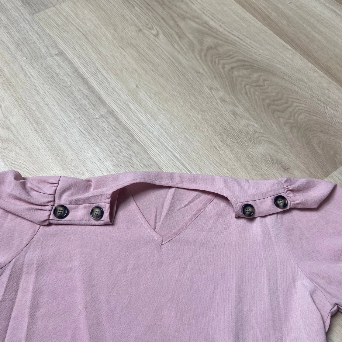 Ljusrosa blus med knappar på axlarna - 1