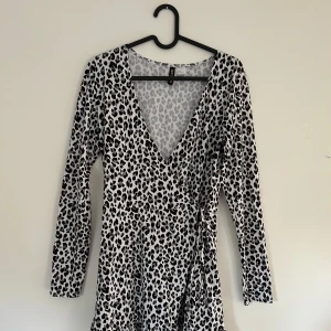Leopardmönstrad omlottklänning från H&M - Knälång leopardmönstrad klänning från H&M med omlott-design och v-ringning. Klänningen har långa ärmar och volangdetalj nedtill. Materialet är extremt mjukt och bekvämt. Nästintill oanvänd.
