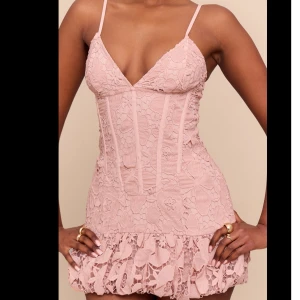 Ljusrosa spetsklänning med volang - Supersöt ljusrosa kortklänning med smala axelband och v-ringad urringning. Nederdelen har en volangkant i spets som ger extra flärd.  Oanvänd. Lapp kvar. Storlek S/36. Nypris 500kr