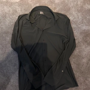 Mörkgrön  skjorta från Stenströms Slimline - Snygg mörkgrön  skjorta från Stenströms Slimline i storlek medium. Skjortan har klassisk krage, lång ärm och knappar framtill. Passformen är slim och materialet känns mjukt och lätt, perfekt för dig som gillar stilrena och enkla plagg.