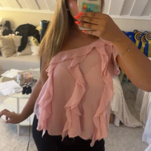 Rosa volangig omlott-top - Söt rosa one shoulder topp från Zara. Köpt här på plick men är i jättebra skick och knappt använd. Storlek M men skulle säga att den passar S💕 