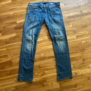 Blå Replay jeans straight fit - Säljer ett par klassiska blå jeans från Replay med snyggt slitna detaljer och raka ben.                                Storlek 33/34 